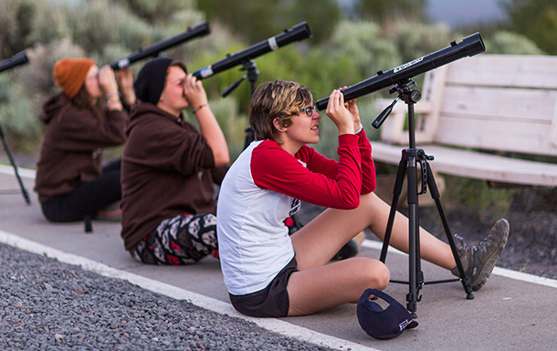 three girls looking through telescopes