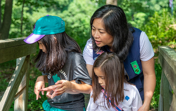 a volunteer and two young girls on bridge