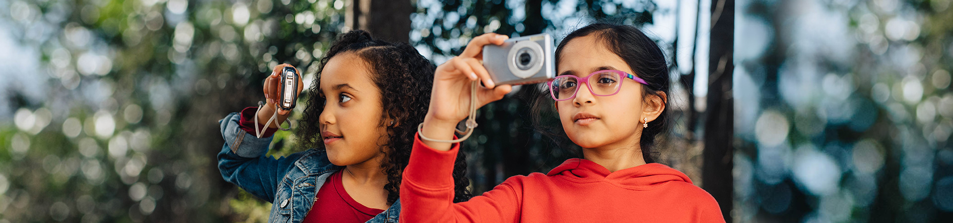  two girl scouts looking through digital cameras 