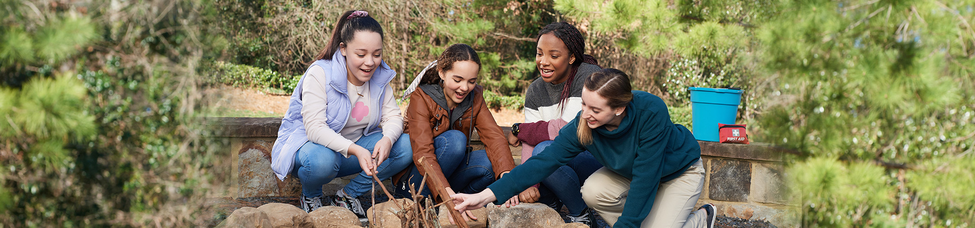  four older girl scouts around a campfire in daylight 