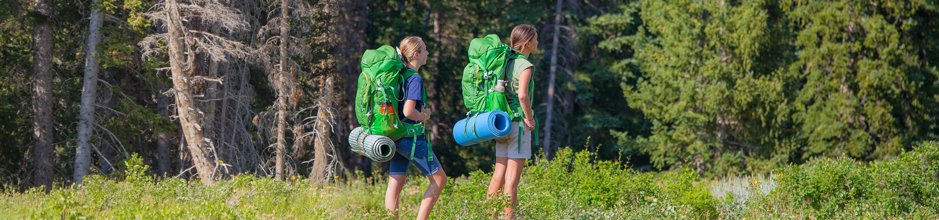  two girls backpacking in a forest 