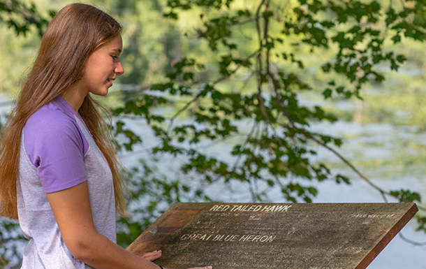 girl reading a sign on a trail