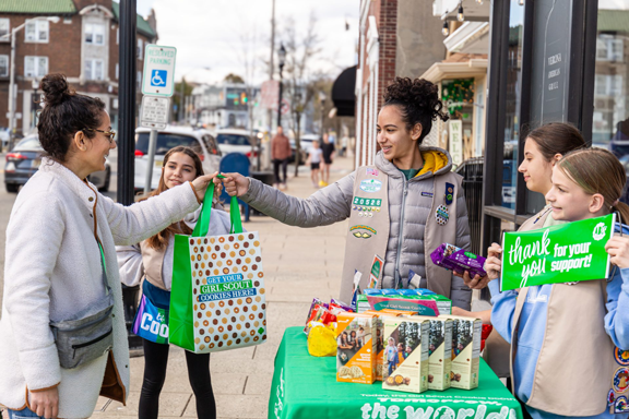 girl scout putting boxes of trefoils into cookie transport bag