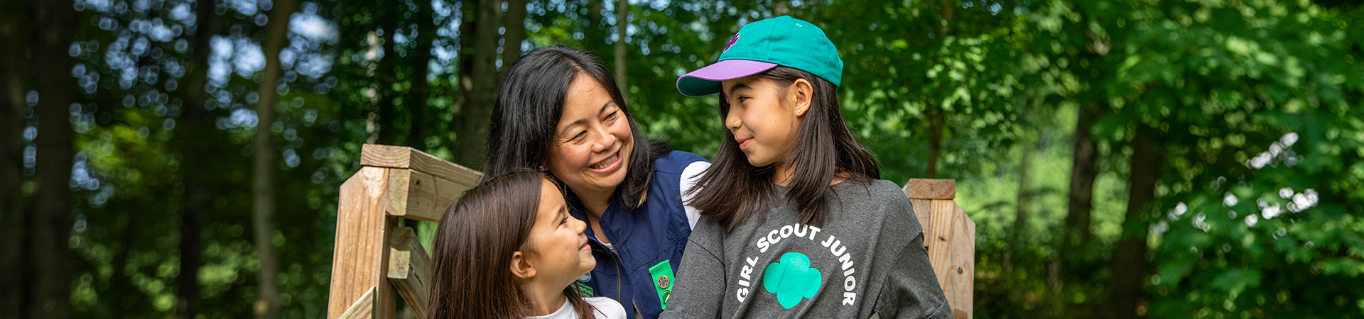 girl scout volunteer smiling at two young girl scouts 